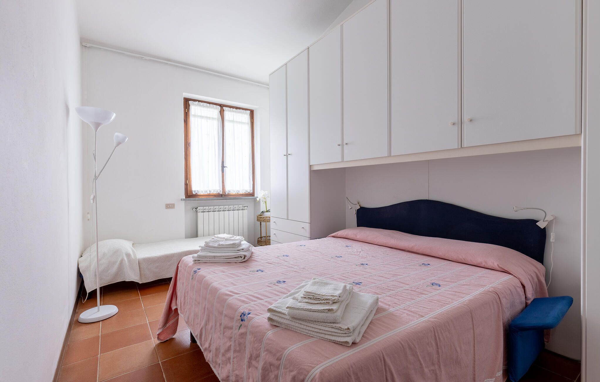 Ein Schlafzimmer mit Bett, Fenster, Heizkörper und Kleiderschrank.