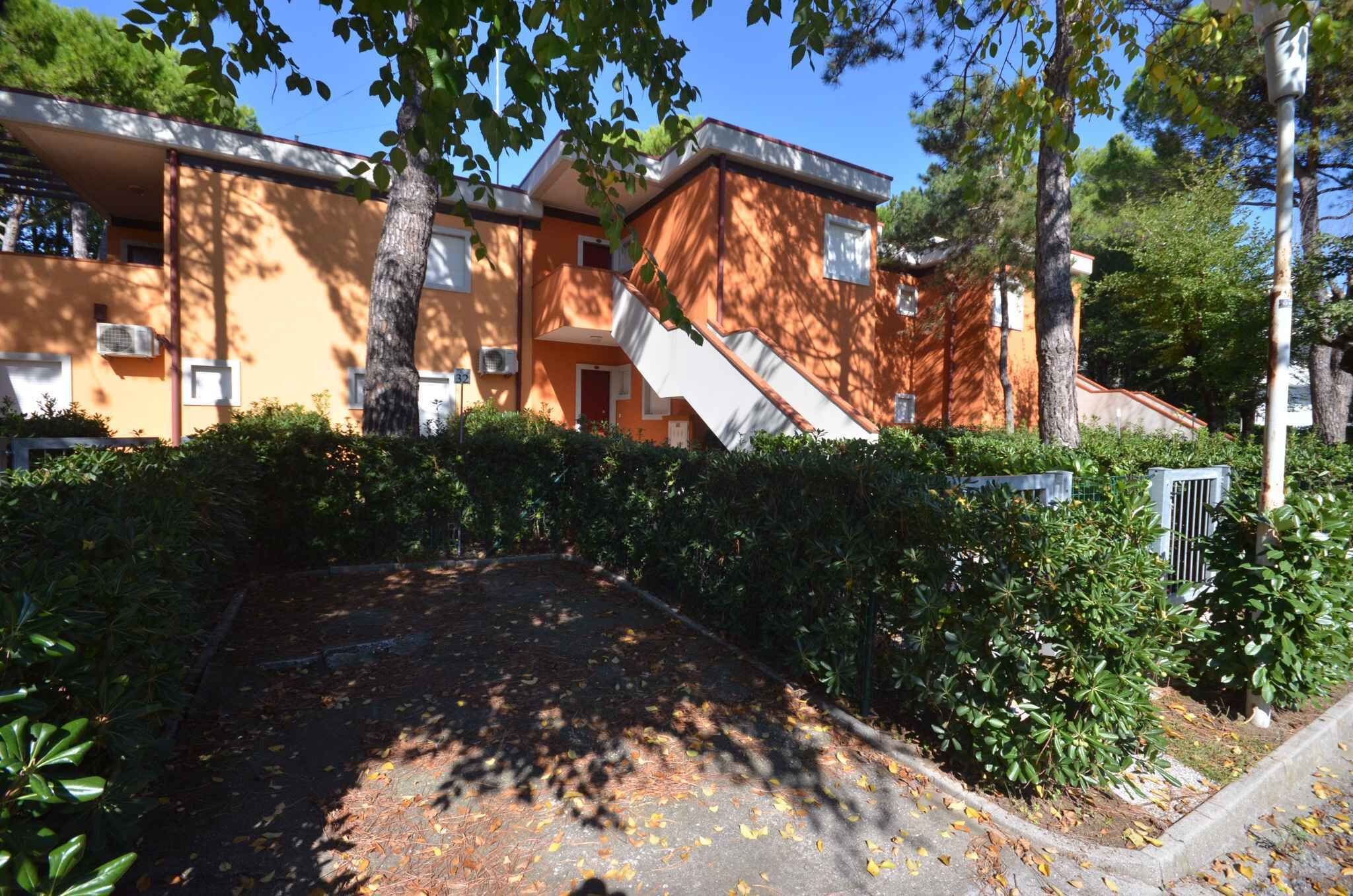 A multi-story residential building with a central staircase, surrounded by dense greenery and a paved driveway.