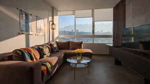 A modern living room with a sofa, a glass coffee table, and a TV.