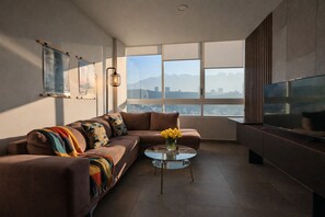 Una sala de estar moderna con un sofá, una mesa de centro de vidrio y un televisor.