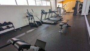 A gym with treadmills, ellipticals, dumbbells, and weight benches.