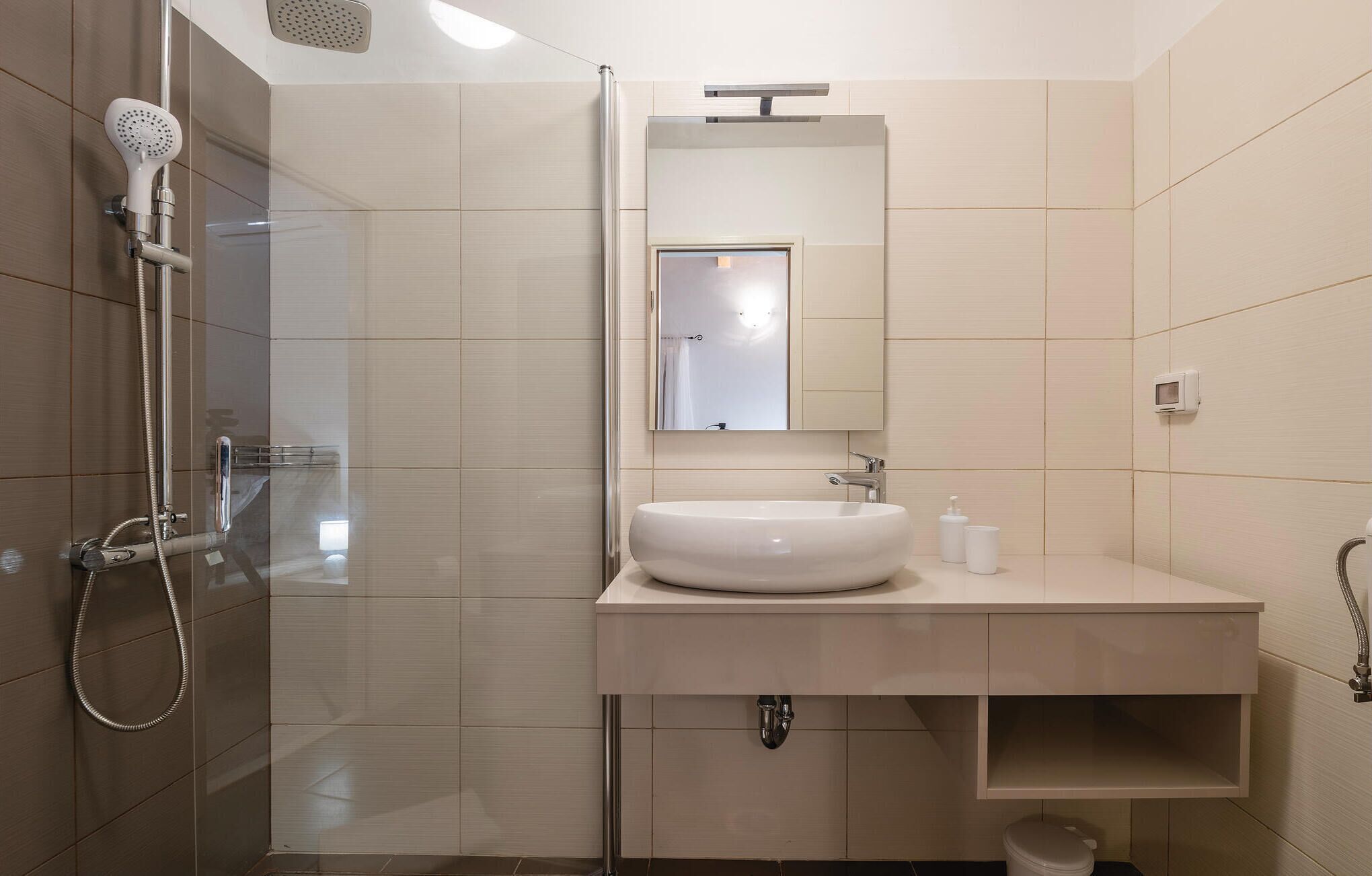 A modern bathroom with a glass-enclosed shower, a white sink, and a mirror above it.