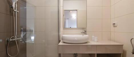 A modern bathroom with a glass-enclosed shower, a white sink, and a mirror above it.