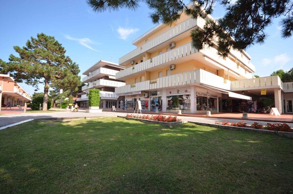 A multi-story building with a central courtyard, featuring a grassy area and a small fountain.