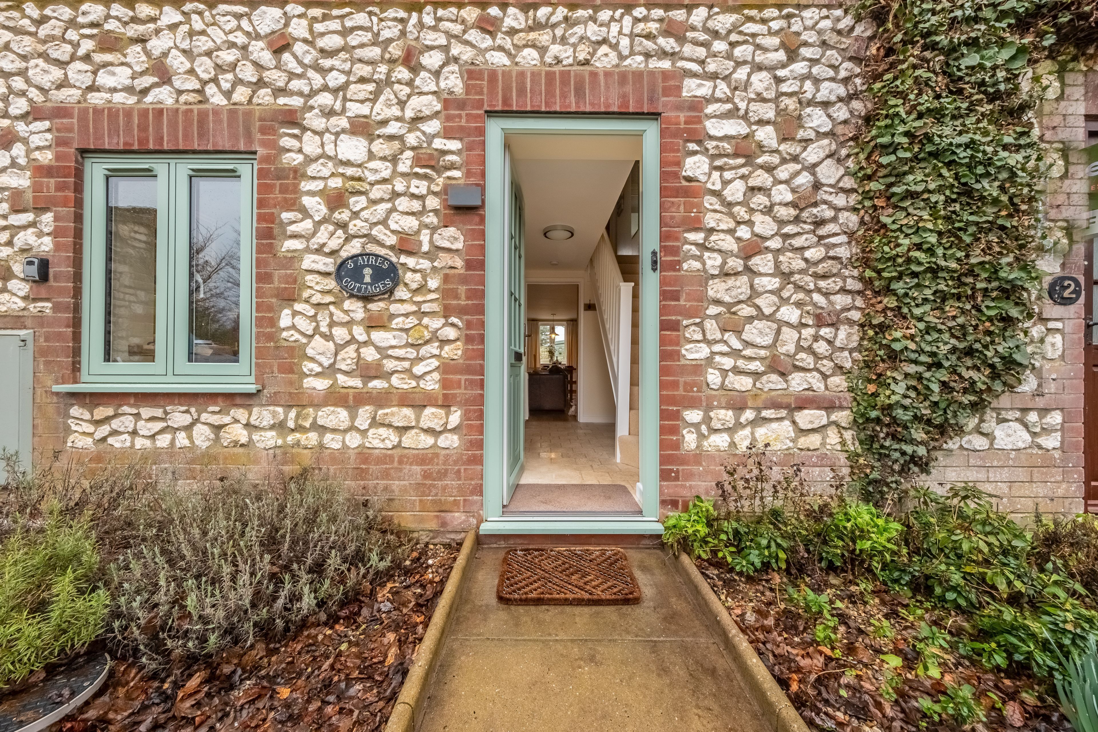 Un bâtiment en pierre avec une porte verte et une enseigne indiquant « 8 AVRES COTTAGE ».