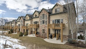 A row of townhouses with stone accents, balconies, and a view of snow-capped mountains. - Stay cool with great rates and central Air conditioning! Weber County lic #3495 (Eden)