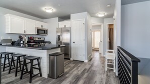 A modern kitchen with white cabinets, stainless steel appliances, and a central island with stools. - Stay cool with great rates and central Air conditioning! Weber County lic #3495 (Eden)