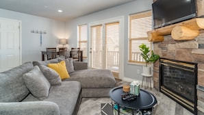 A living room with a gray sectional sofa, a fireplace, and a mounted TV. - Stay cool with great rates and central Air conditioning! Weber County lic #3495 (Eden)