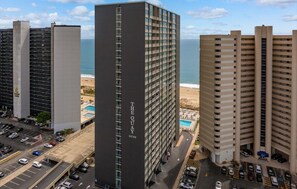 Um hotel moderno com piscina, estacionamento e vista para a praia.