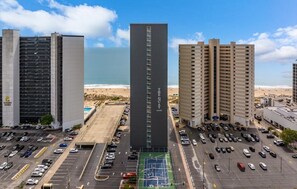 A high-rise hotel with a central tower, parking lots, and a beach view. - Come Stay at This Beautiful Unit From HGTV's - Island Life! (Ocean City)