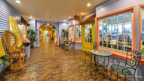 A corridor with wicker chairs, a small table, and a window with a view of the city. - Come Stay at This Beautiful Unit From HGTV's - Island Life! (Ocean City)
