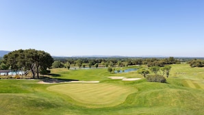 Un campo de golf con búnkeres, obstáculos de agua y un club house.