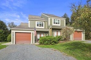 A two-story house with a front garage, a small front yard, and a driveway. - Topnotch Resort Home - Private Hot Tub (Stowe)