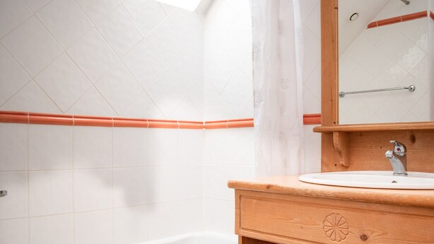 A bathroom with a white bathtub, wooden vanity, and a mirror.