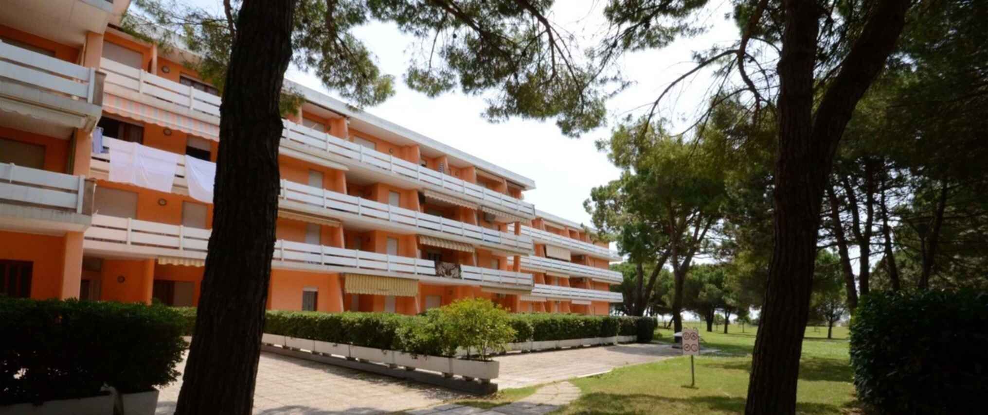 A multi-story hotel with balconies and a well-maintained garden.