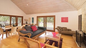 A spacious living area with a wooden ceiling, a sofa, a coffee table, and a fireplace. - Yallingup Retreat - *Romantic, overlooking a lake, secluded* (YALLINGUP)
