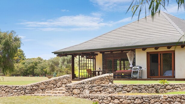 A house with a stone retaining wall, a covered patio, and a barbecue area. - Yallingup Retreat - *Romantic, overlooking a lake, secluded* (YALLINGUP)