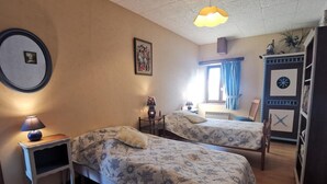 Une chambre avec deux lits, un bureau, une chaise et une armoire.