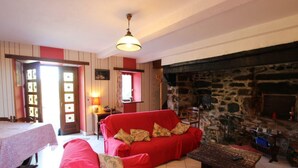 Une pièce chaleureuse avec un canapé rouge, une table en bois et une cheminée en pierre.