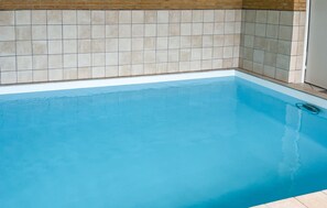 Una piscina con un muro de azulejos y un borde blanco.