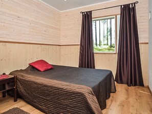 Un dormitorio con cama, mesita de noche y ventana con cortinas.