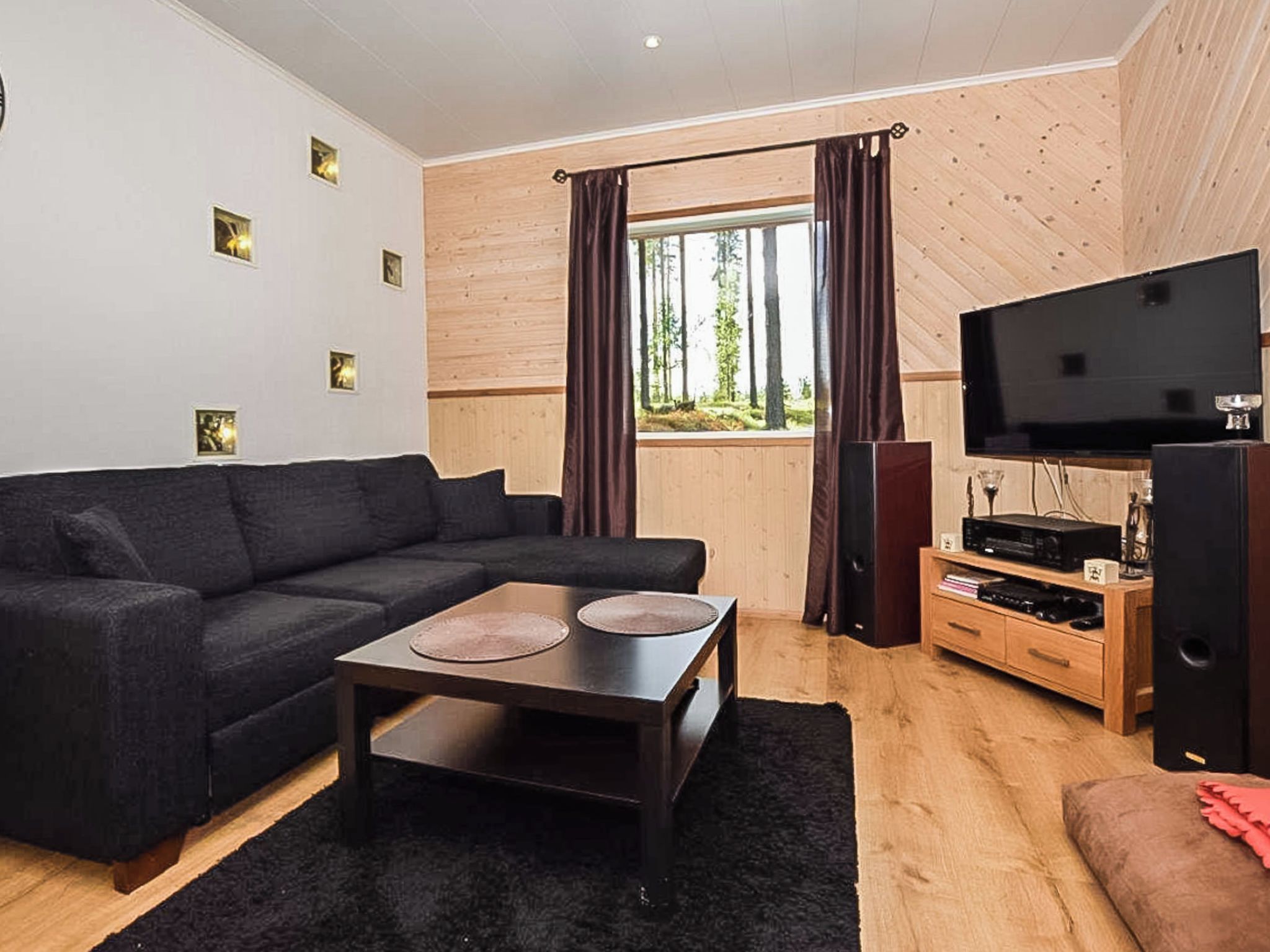Un salon moderne avec un canapé d’angle, une table basse, un téléviseur et un meuble de rangement en bois.