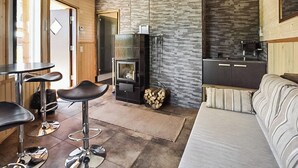 Ein modernes Wohnzimmer mit Kamin, einer Küchenzeile und einer Sitzecke mit einer Couch und Barhocker.