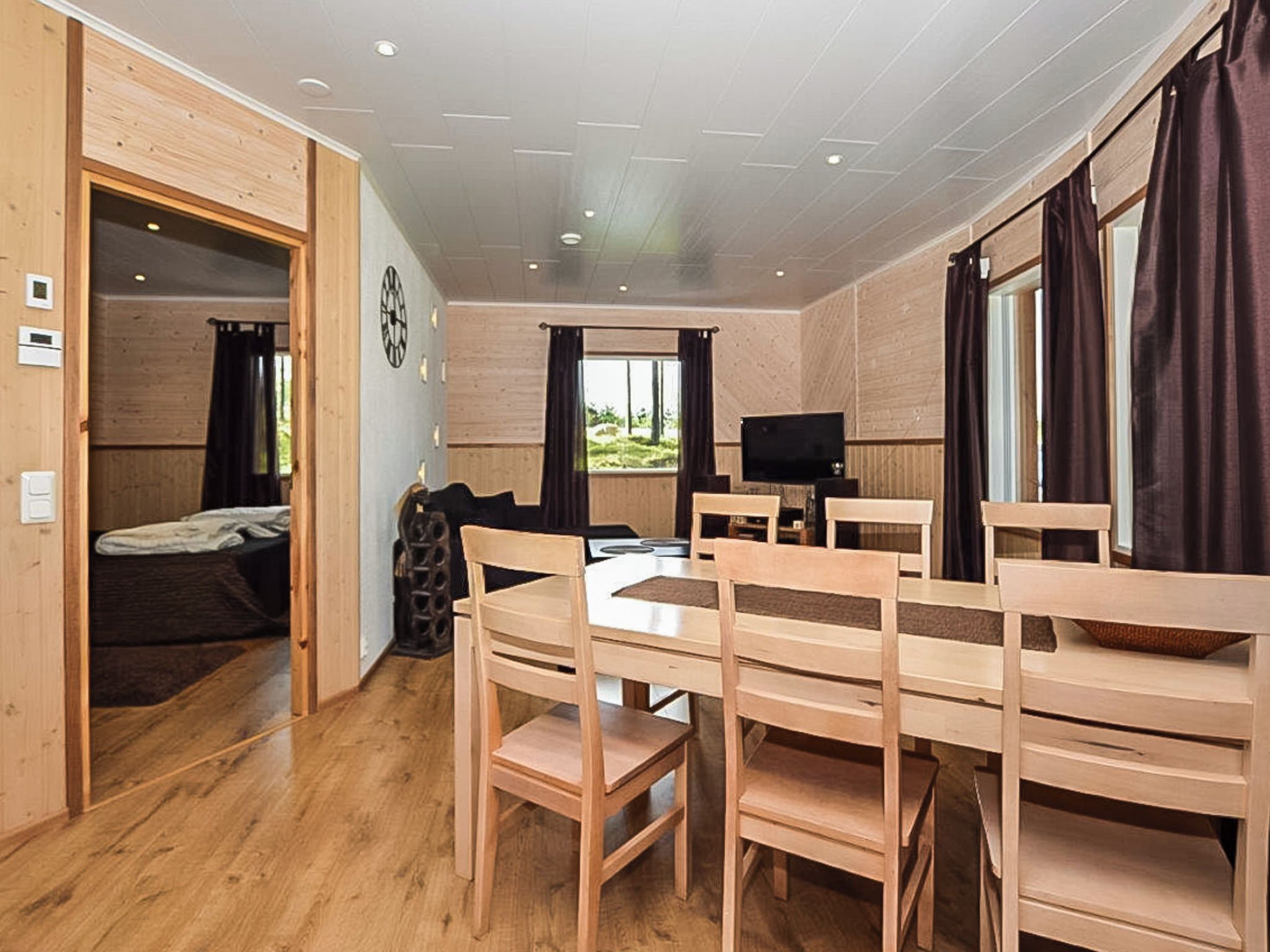 Un espacio habitable compacto con comedor, televisor y cama.