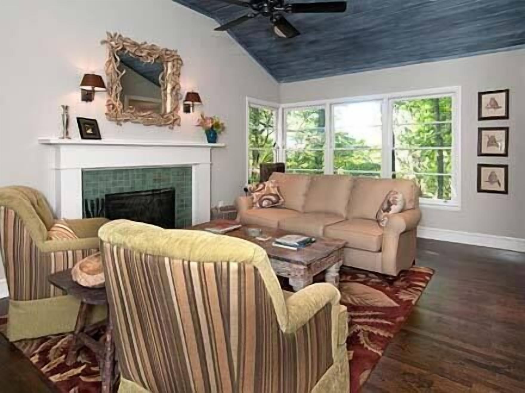 A living room with a fireplace, a sofa, a striped armchair, and a coffee table.