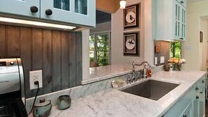 A modern kitchen with marble countertops, a double sink, wooden cabinets, and a visible coffee maker. - Relaxing Stay in Black Mountain, NC (Black Mountain)