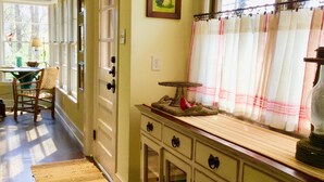 A kitchen with wooden cabinets, a window with curtains, and a door leading to another room. - Relaxing Stay in Black Mountain, NC (Black Mountain)