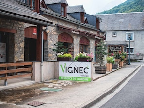 Un bâtiment en pierre avec une enseigne indiquant « VIGNEC, village » et « RÉSIDENCE TOURISTIQUE ».