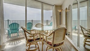 Ein Balkon mit Glastisch und Stühlen, der auf eine Brüstung und entfernte Gebäude blickt.