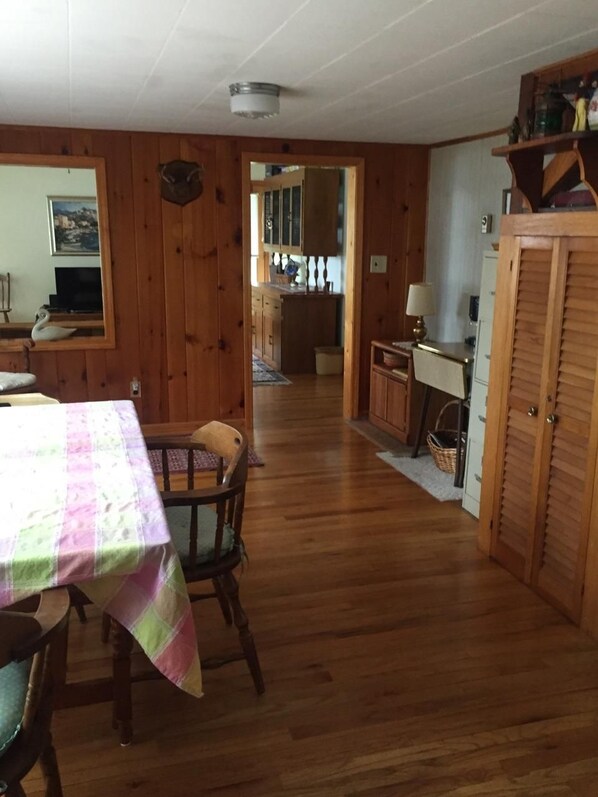 A wooden interior with a dining table, chairs, a kitchen area, and a wardrobe. - Spacious, private, very desirable 3-bedroom lakefront cottage in the FIngerlakes (Skaneateles)