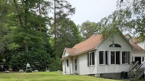 A house with a sloped roof, a front porch, and a well-maintained lawn. - Spacious, private, very desirable 3-bedroom lakefront cottage in the FIngerlakes (Skaneateles)