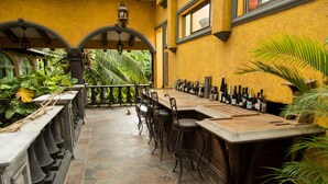 A bar area with a stone-tiled floor, bar stools, and a variety of bottles.