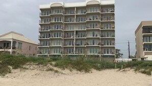 A multi-story hotel with balconies, located near a sandy beach. - Private 2nd floor balcony facing the Gulf, sleeps 6. Pool & hot tub (South Padre Island)