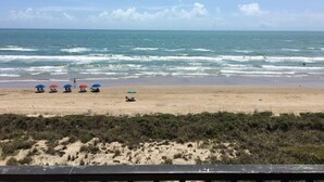 A beach with several umbrellas and a sandy shore. - Private 2nd floor balcony facing the Gulf, sleeps 6. Pool & hot tub (South Padre Island)