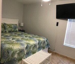 A bedroom with a bed, a TV mounted on the wall, a nightstand, and a window with blinds. - Private 2nd floor balcony facing the Gulf, sleeps 6. Pool & hot tub (South Padre Island)