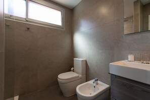 A modern bathroom with a toilet, bidet, and sink.