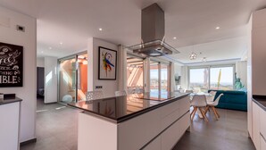 A modern kitchen with a central island, a dining area with chairs, and a view of the city.