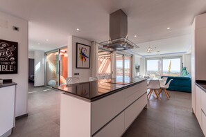 A modern kitchen with a central island, a dining area with chairs, and a view of the city.