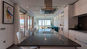 A modern kitchen with a central island, white cabinetry, and a large window offering a view.