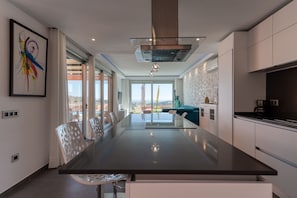 Una cocina moderna con una isla central, armarios blancos y un ventanal con vistas.
