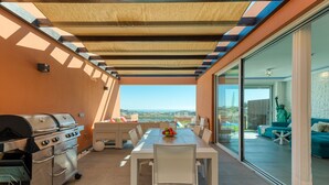 An outdoor patio with a grill, dining table, and chairs.