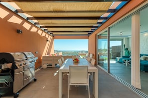 Un patio al aire libre con una parrilla, mesa y sillas.