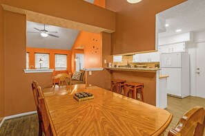 A dining area with a wooden table and chairs, a kitchen with white cabinets, and a ceiling fan. - "SW Houston Eclectic Living" Long Stays Welcome! (Houston)