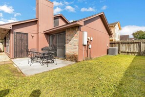 Una casa residencial con un patio, una chimenea de ladrillo y una valla de madera.