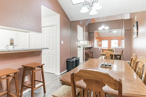 Enjoy meals in this stylish kitchen and dining area with a long wooden table and comfortable seating.