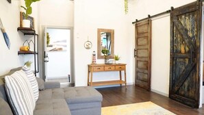 A living room with a gray sofa, wooden console table, and a large mirror. - Rivers Edge Lofts - Unit 4 (Niles)